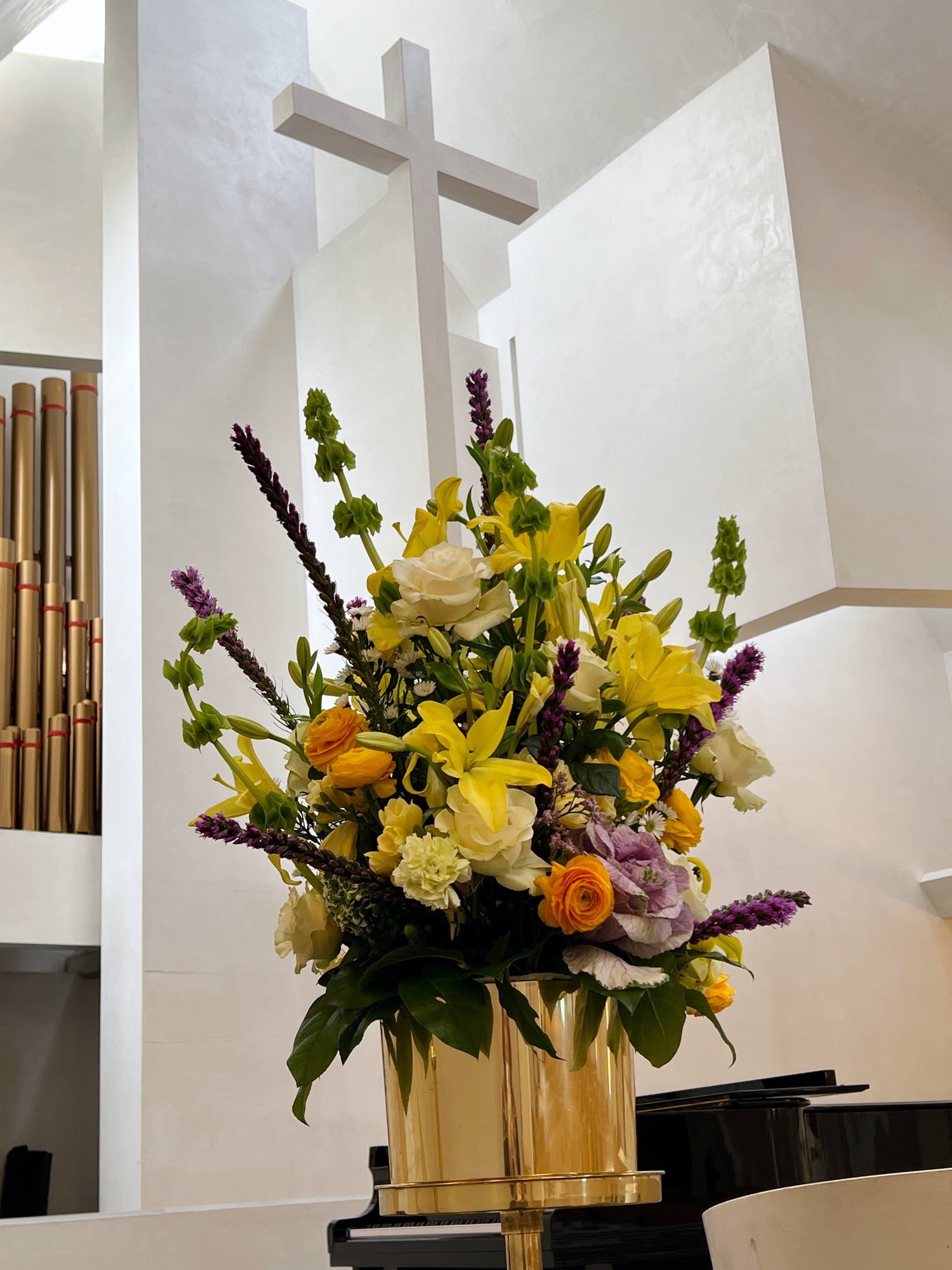 Statement church altar floral arrangement with lilies, roses, ranunculus, cabbage roses, and bells of Ireland