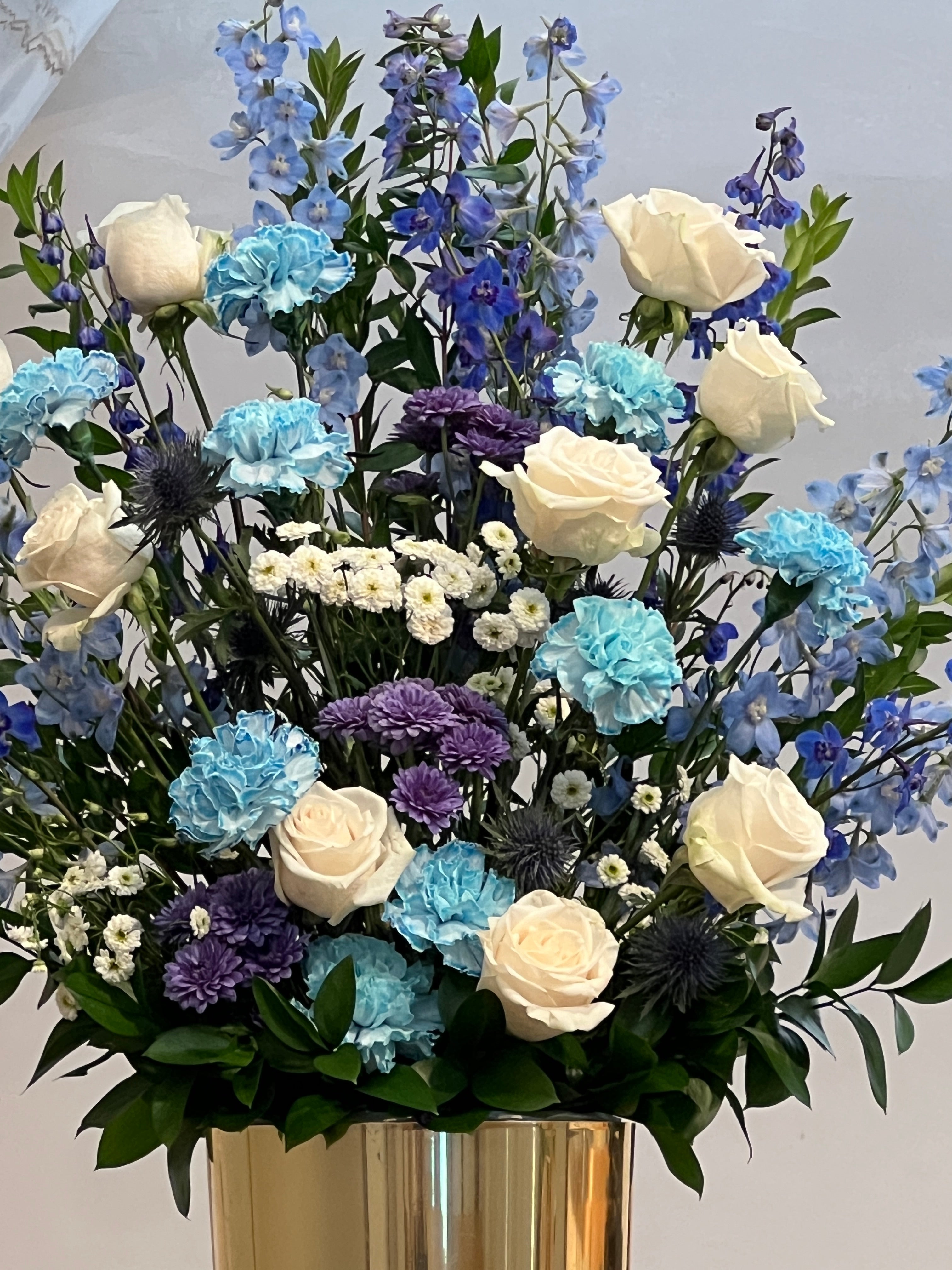 Elegant celebration of life arrangement with blue delphinium, white roses, and carnations – Los Angeles funeral florist