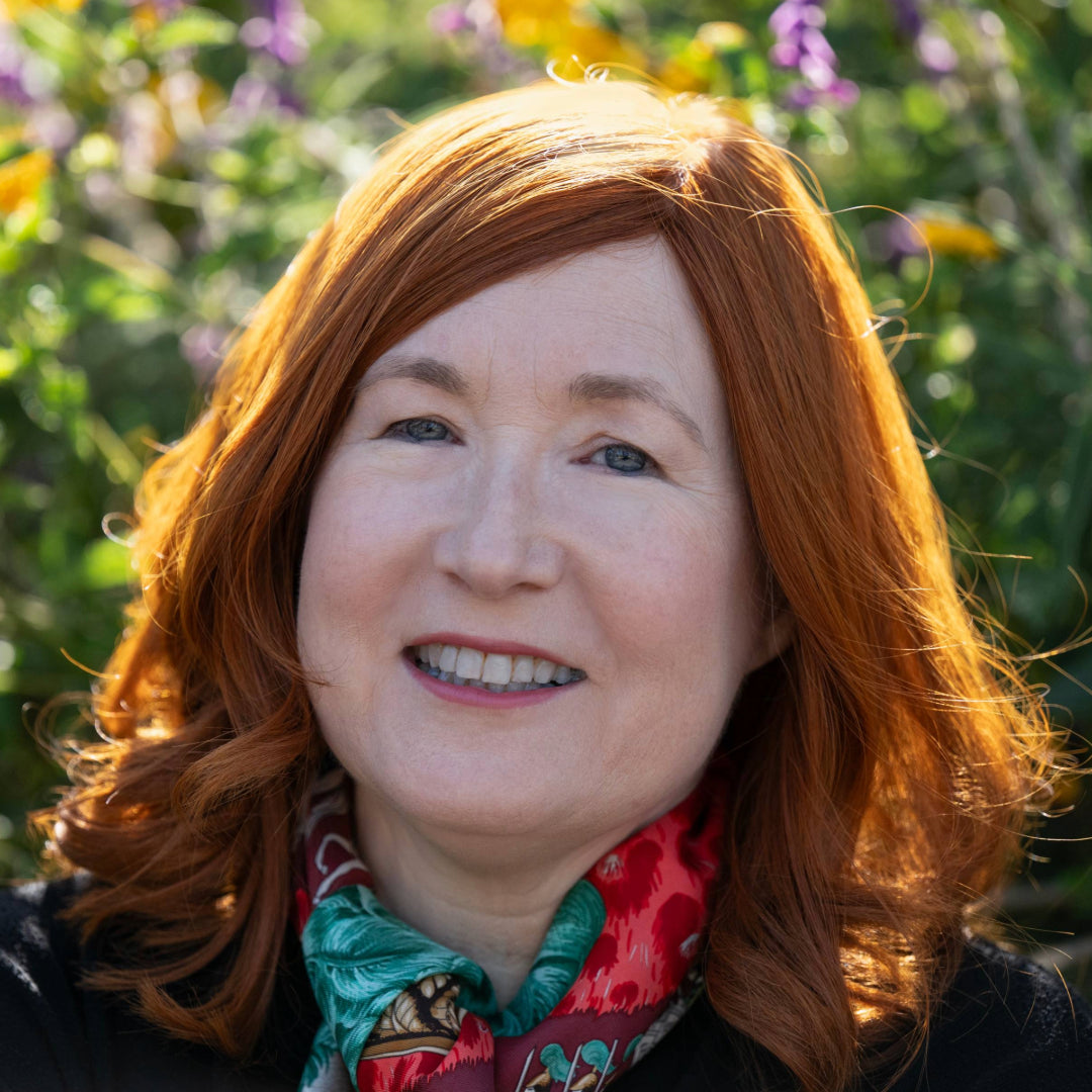 Headshot of Janice Pearson with yellow and purple flowers blurred in the background.