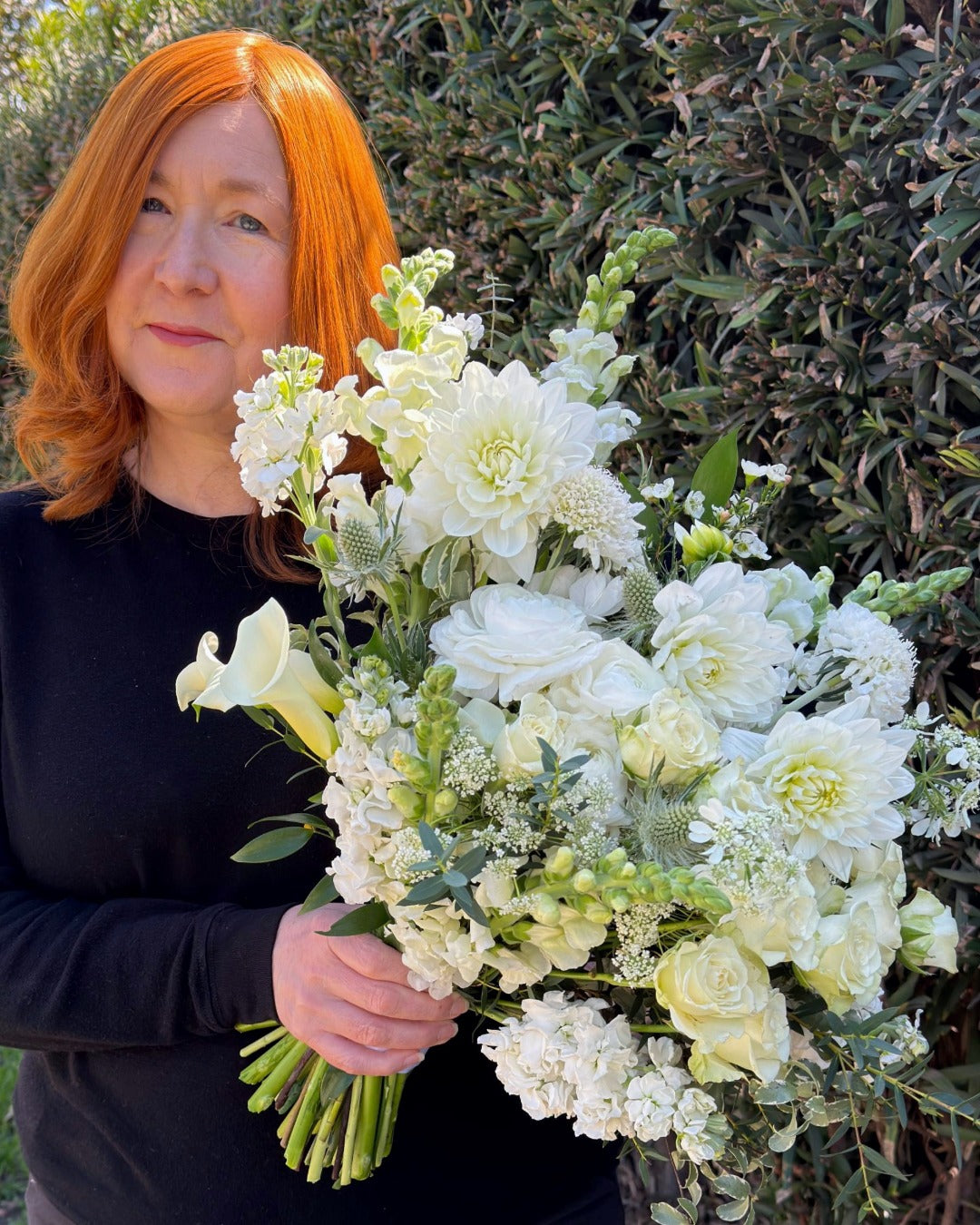 Pearson Floral Designs founder holding a luxury white bridal bouquet featuring dahlias, calla lilies, snapdragons, and roses.