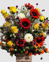 Bright floral arrangement with red sunflowers, yellow roses, white dahlias, safflower, and gomphrena.
