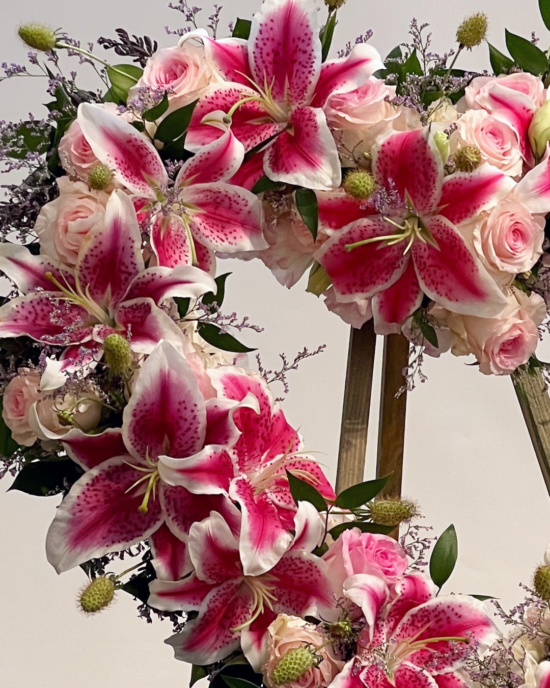 Closeup of open heart wreath with stargazer lilies and Vendala white and pink roses for celebration of life service.