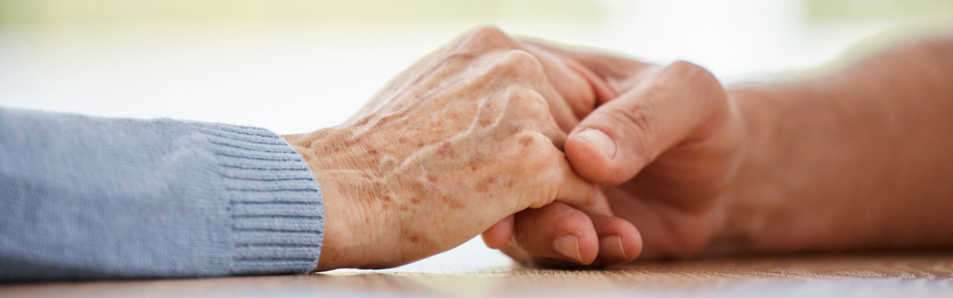 A comforting close-up of two hands gently holding during a celebration of life or funeral service.