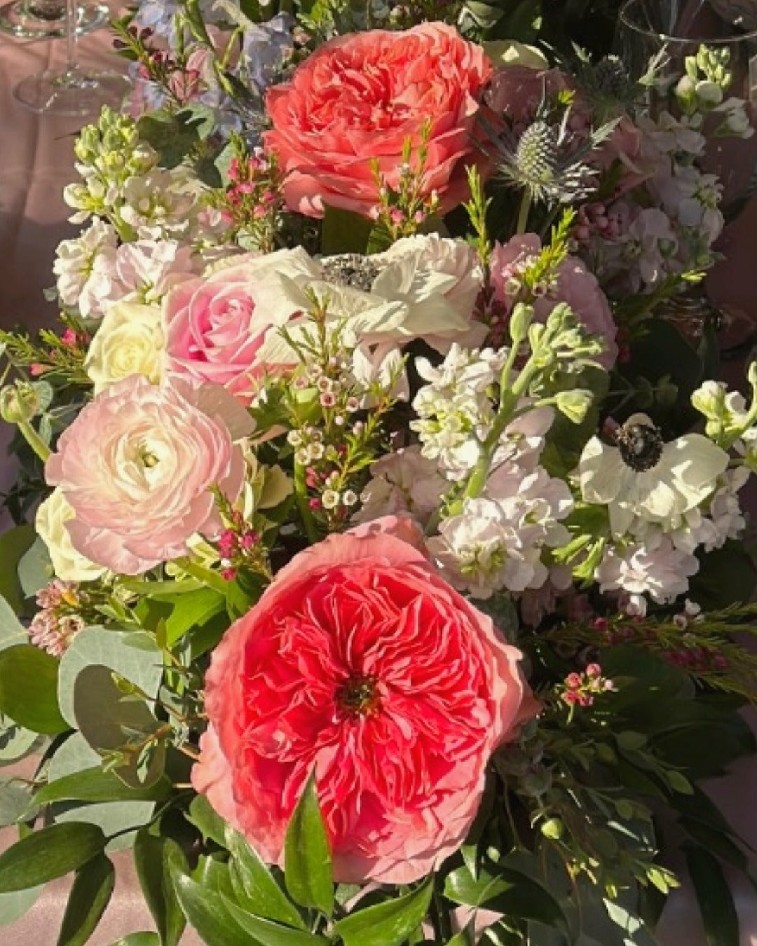 Close-up of reception florals from the 40 foot garden-style floral table runner featuring roses, stock, wax flower, and delphinium.