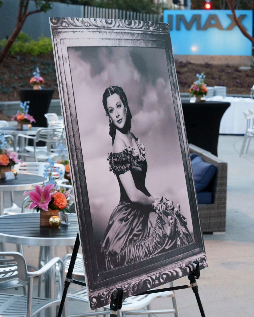 Vintage-style portrait of Hedy Lamarr with floral arrangements in the background for a DEG Canon Club award event. 