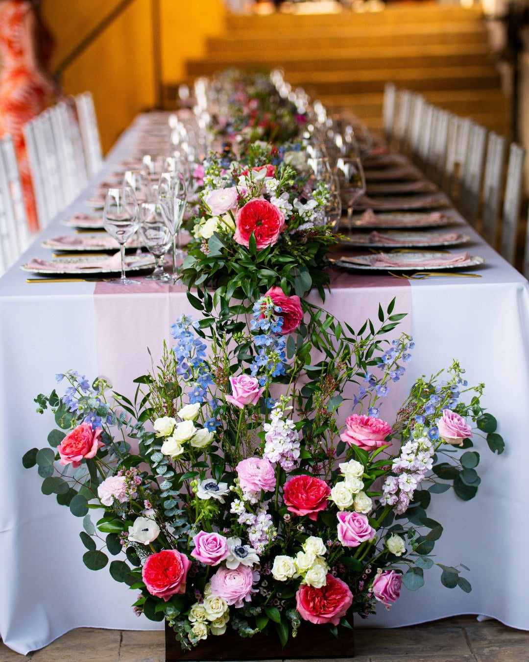 Forty foot table set for a vow renewal reception featuring a garden-style floral runner viewed from the end of the table