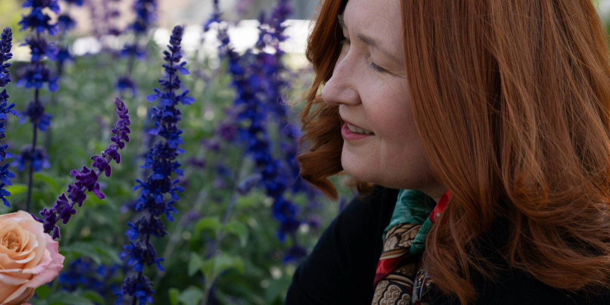 Janice Pearson holding a peach rose in a garden of Mexican Bush Sage and Salvia Merleau Blue.