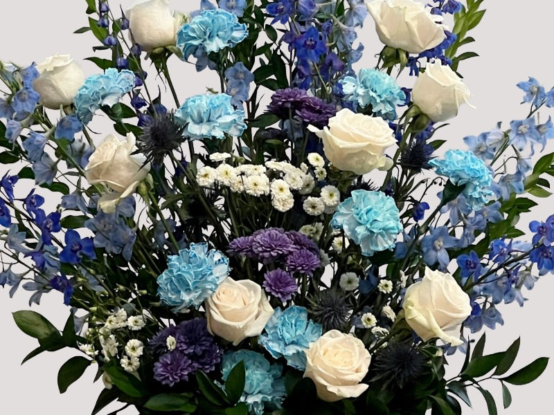 Elegant blue and white floral arrangement with roses, delphinium, and carnations for a Los Angeles celebration of life service.