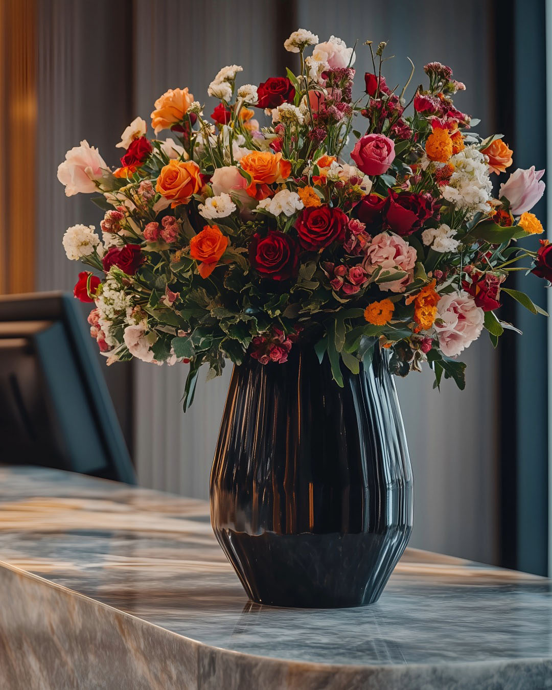 Luxury floral arrangement in a black vase styled for a hotel lobby or hospitality space with rich color, texture, and scale.