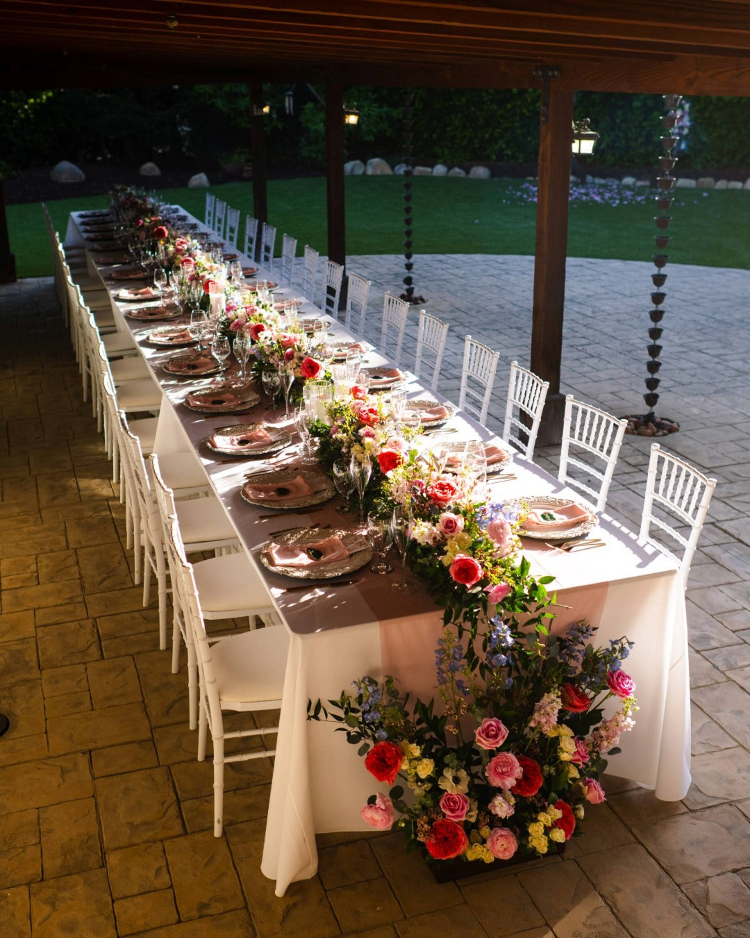 Forty foot table set for a wedding reception featuring a floral runner that cascades to the ground