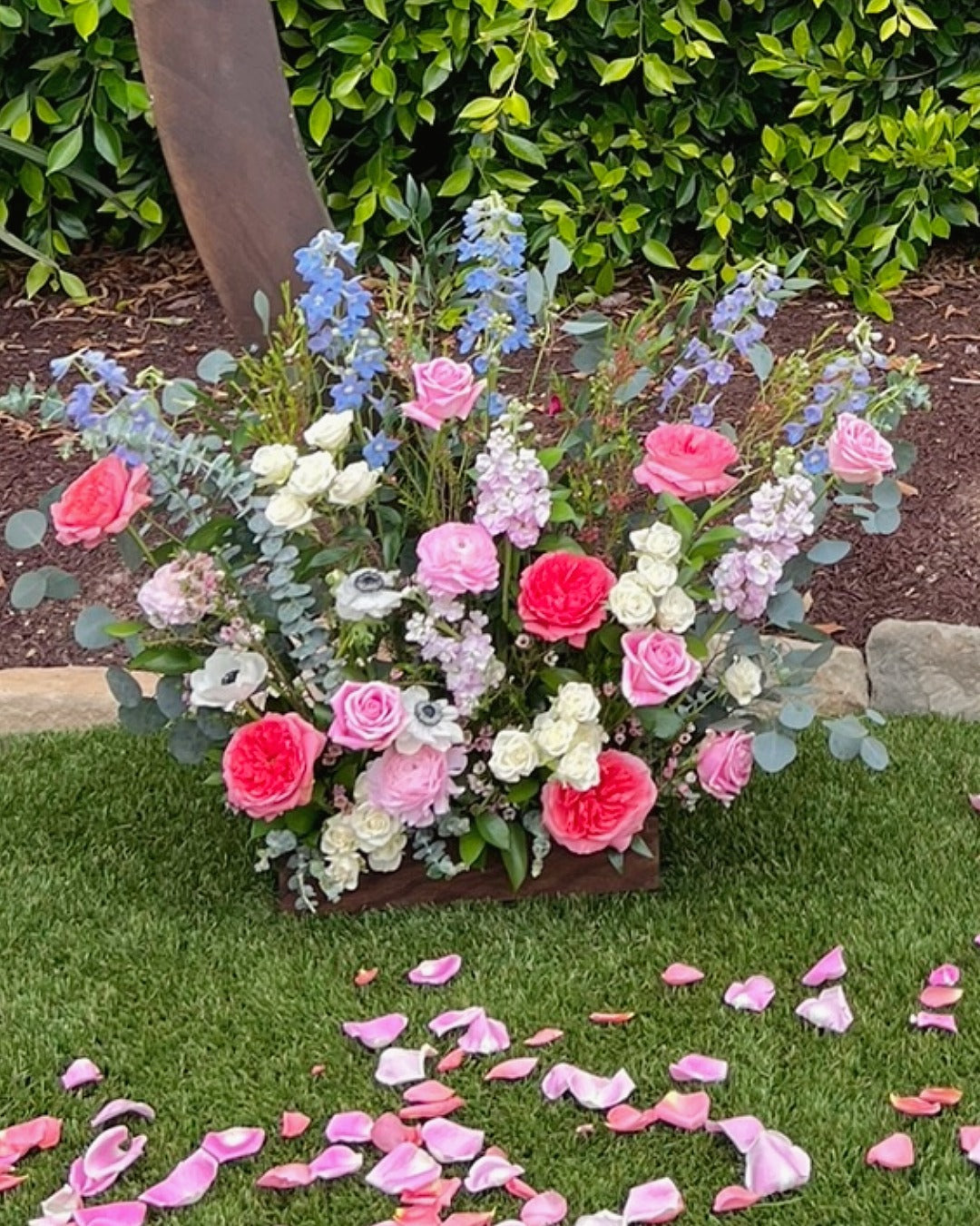 Bottom arch piece closeup featuring roses, anemones, delphinium, stock, and eucalyptus.