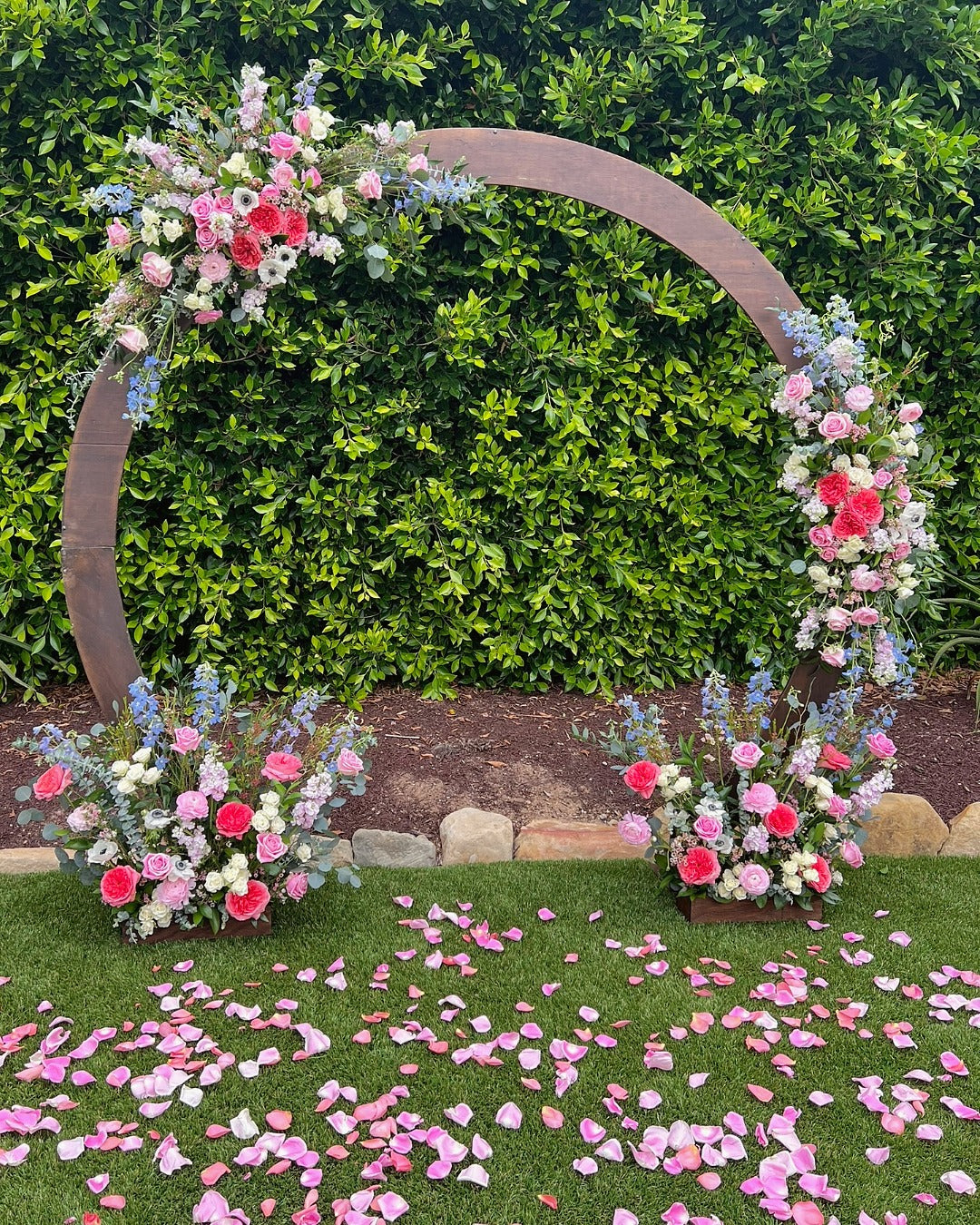 Wedding arch for vow renewal ceremony featuring roses, anemones, delphinium, stock, wax flower, eucalyptus and Italian Ruscus.