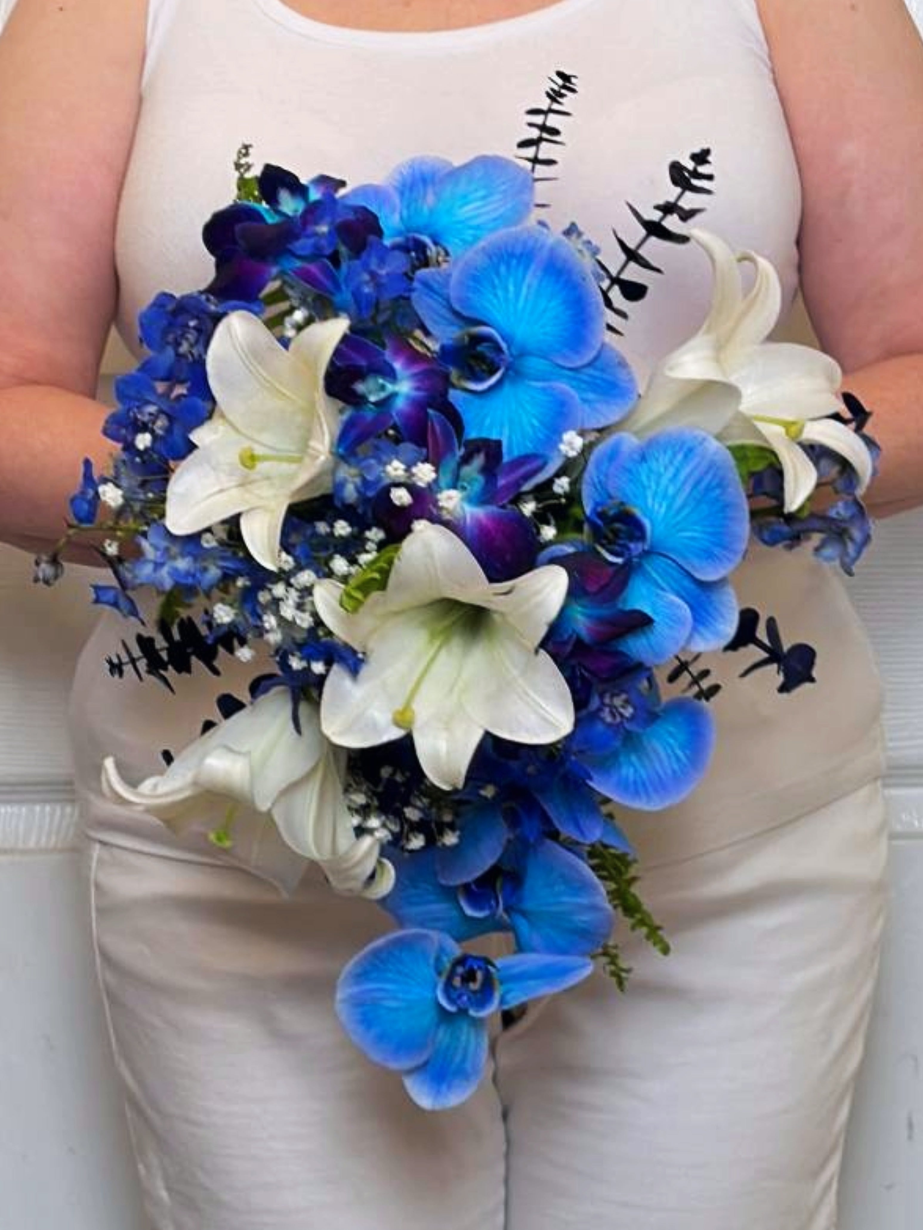 Bridal bouquet of blue phalaenopsis orchids, indigo dendrobium orchids, Easter lilies, and electric blue delphinium.