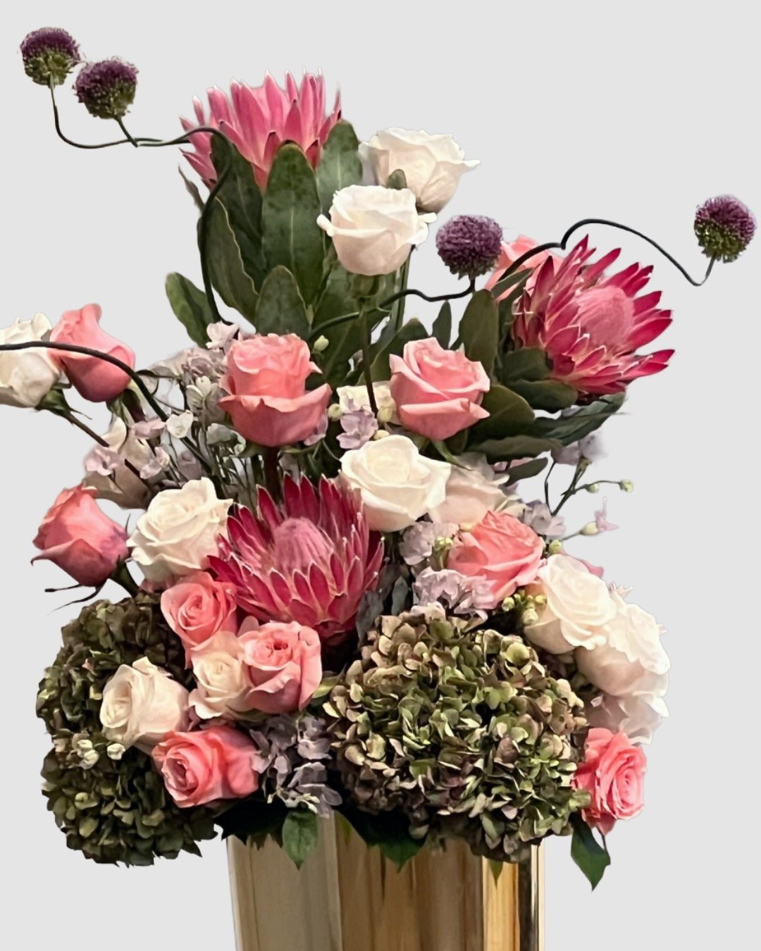 Luxury garden-style arrangement with protea, roses, antique hydrangeas, delphinium, and dancing allium.