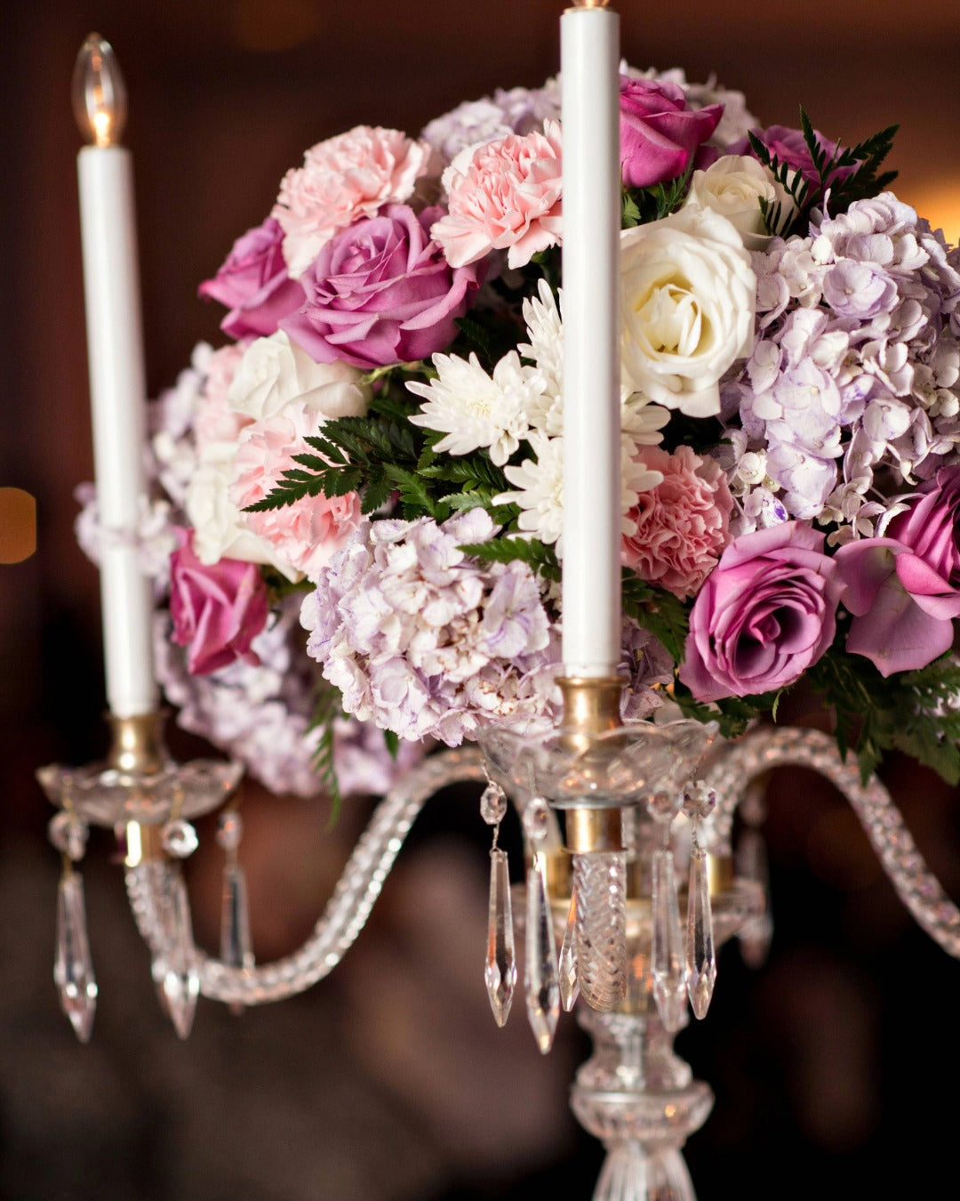 Close-up of crystal candelabra with lavender, pink, and white flowers for ballroom wedding.