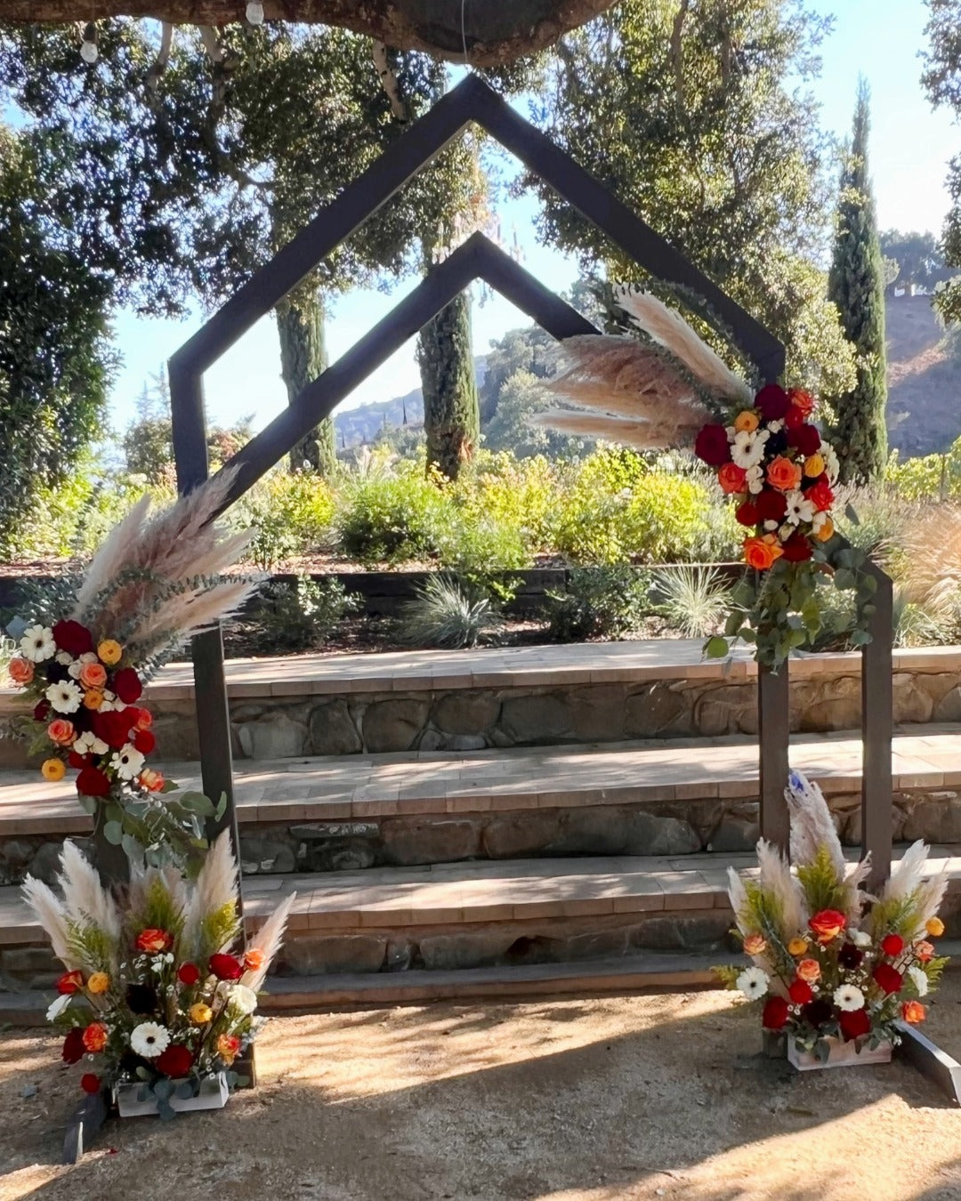 Wedding arch for a vineyard wedding featuring pampas grass, dahlias, roses, and gerbera daisies in fall colors.