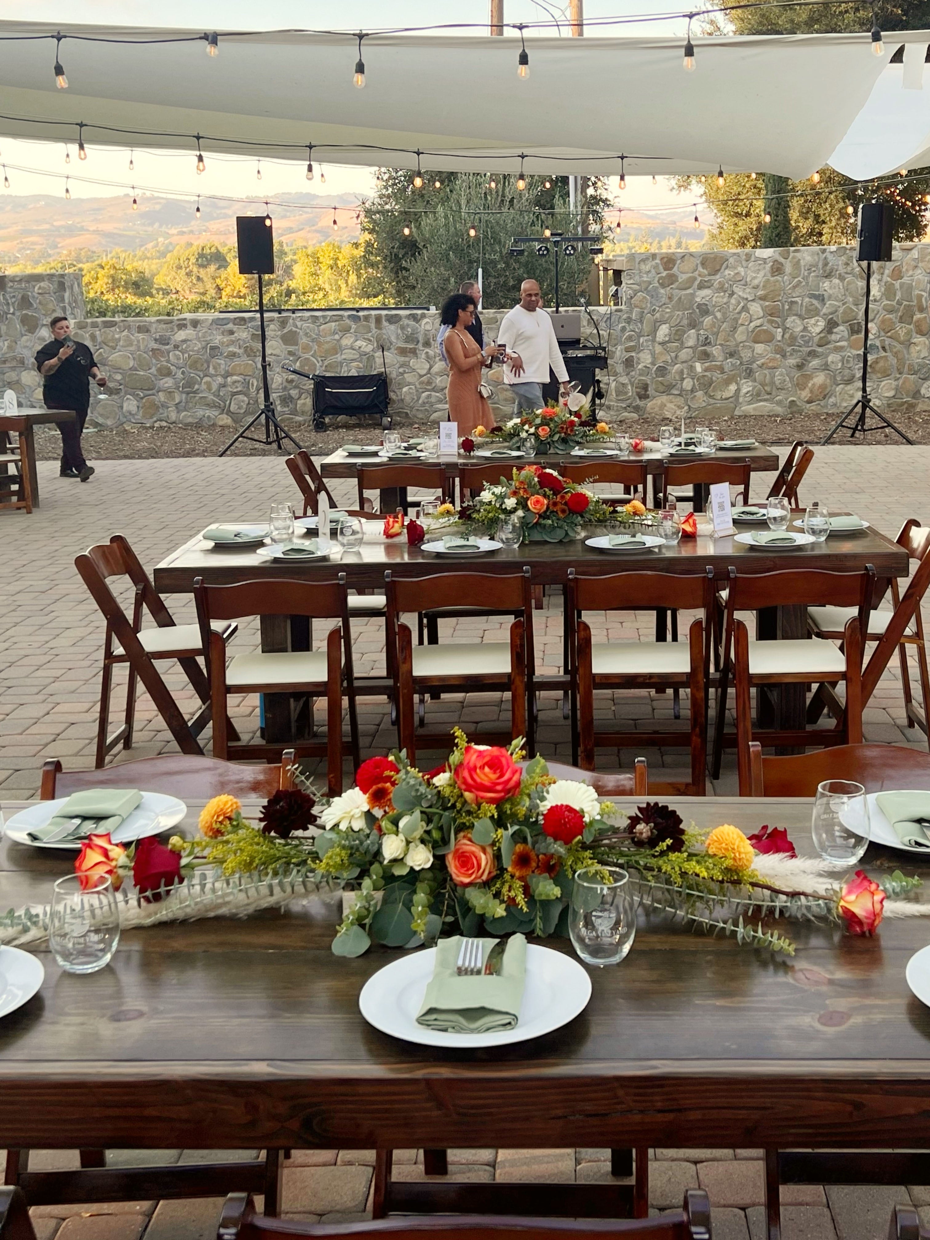 Vineyard wedding reception table with long arrangement on 8 foot wooden tables.
